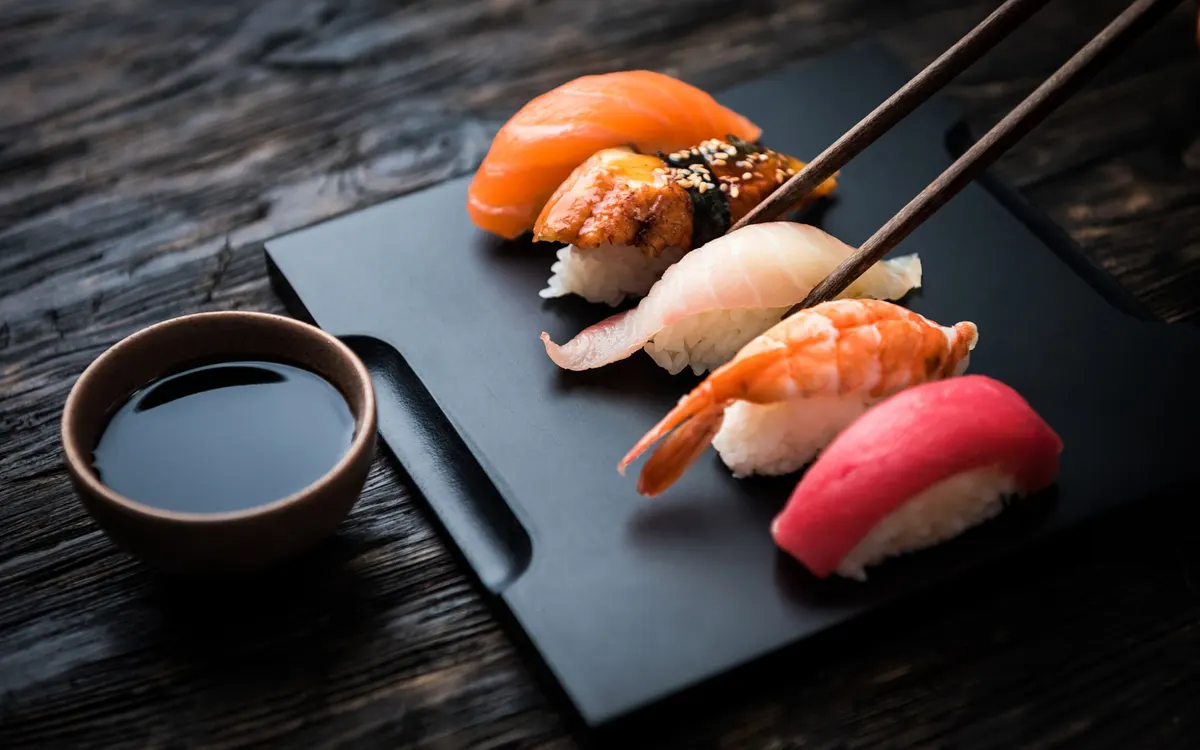 Nigiri mit Lachs, Aal, Weißfisch, Garnele und Thunfisch auf schwarzer Platte