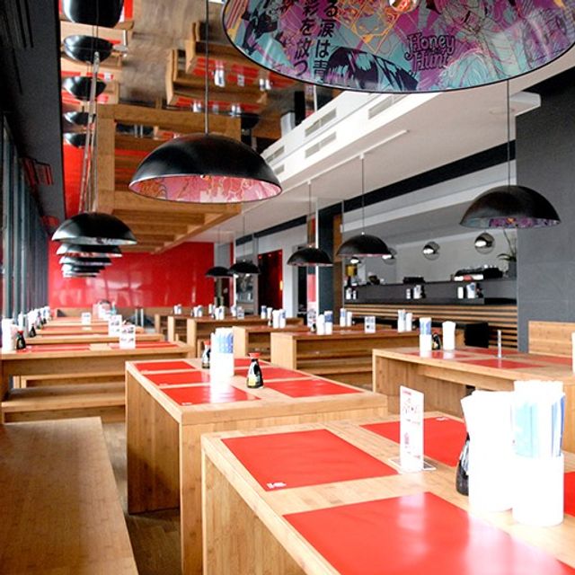 Gastraum der Bento Box Köln mit Holztischen, roten Tischsets und schwarzen Pendelleuchten